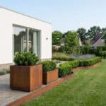 Cortenstaal plantenbak met natuurlijke roestkleur en groene beplanting.
