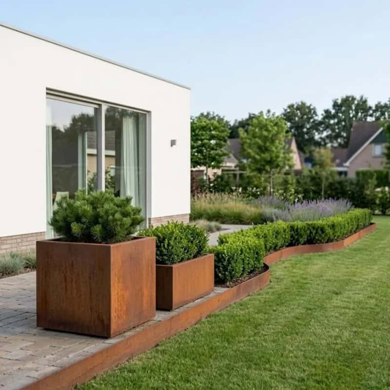 Cortenstaal plantenbak met natuurlijke roestkleur en groene beplanting.
